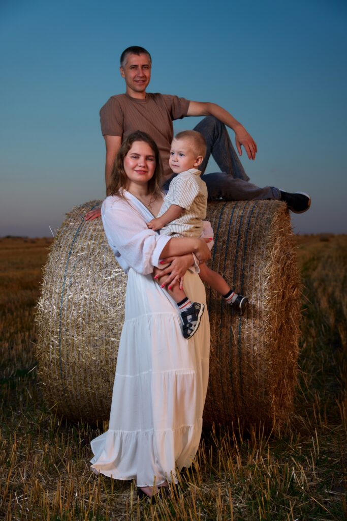 Семейная фотосессия на природе в Ростове-на-Дону — мама, папа и сын у тюка сена в поле