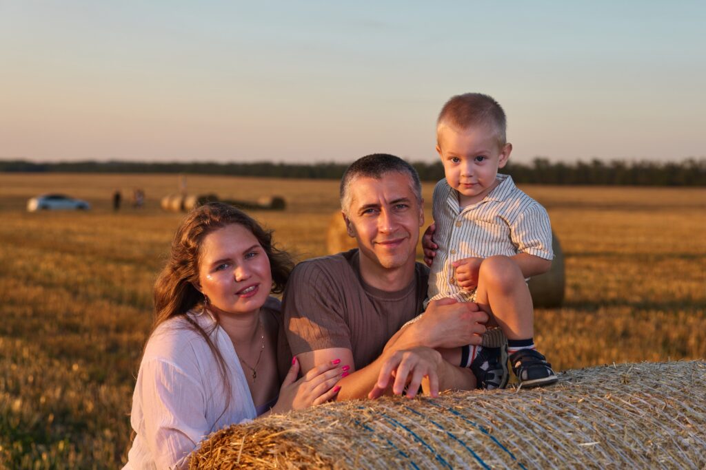 Семейная фотосессия на природе в Ростове-на-Дону — мама, папа и сын у тюка сена в поле